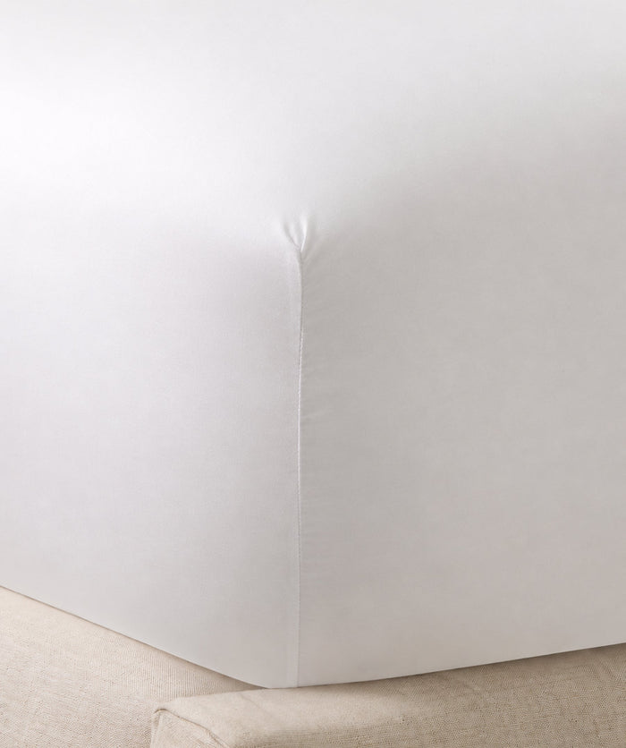 Close-up of a white fitted sheet stretched smoothly over a mattress corner.