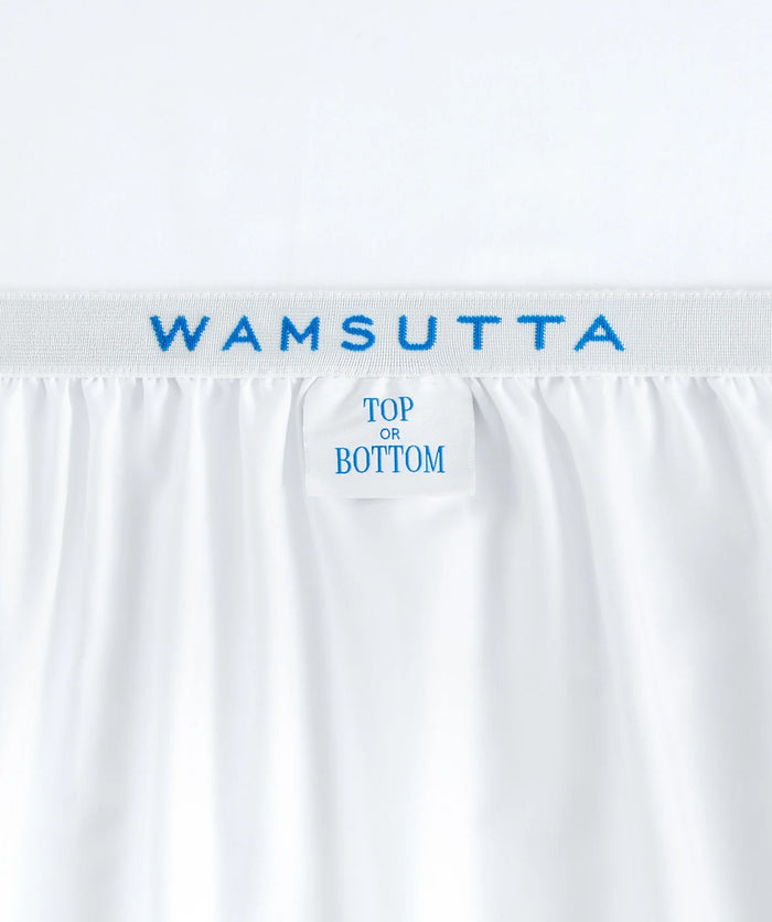 Close-up of white fitted sheet elastic featuring Wamsutta branding and a “Top or Bottom” label.